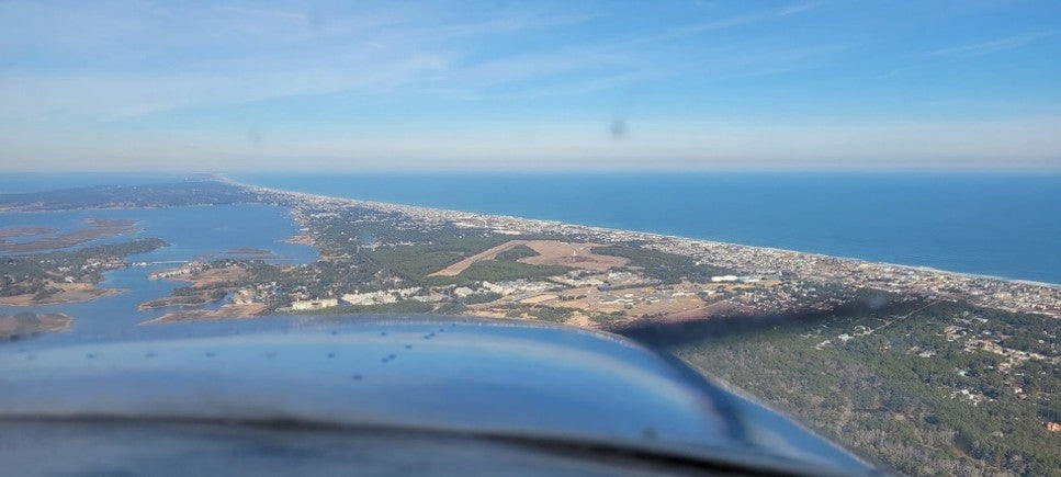 Atlantic barrier island coastline stretching to the horizon, seen over the cowling