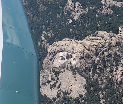 Mount Rushmore in the Black Hills seen from the air past a light aircraft wing