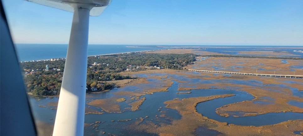 Salt marsh and barrier island on the Atlantic coast seen past the wing strut from the left seat